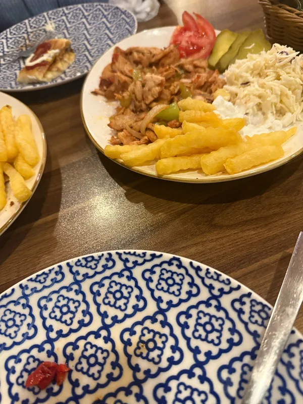 Shawarma plate with fries and coleslaw next to a blue-and-white patterned plate
