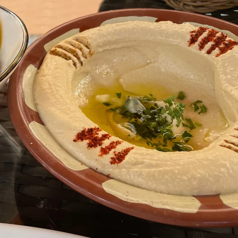 Hummus in a clay dish with olive oil and paprika